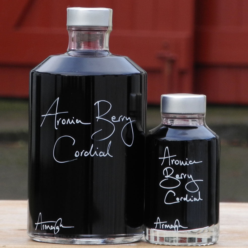 Aronia Berry Cordial in a 500ml bottle and 100ml bottle with handwritten bottle message in white pen.