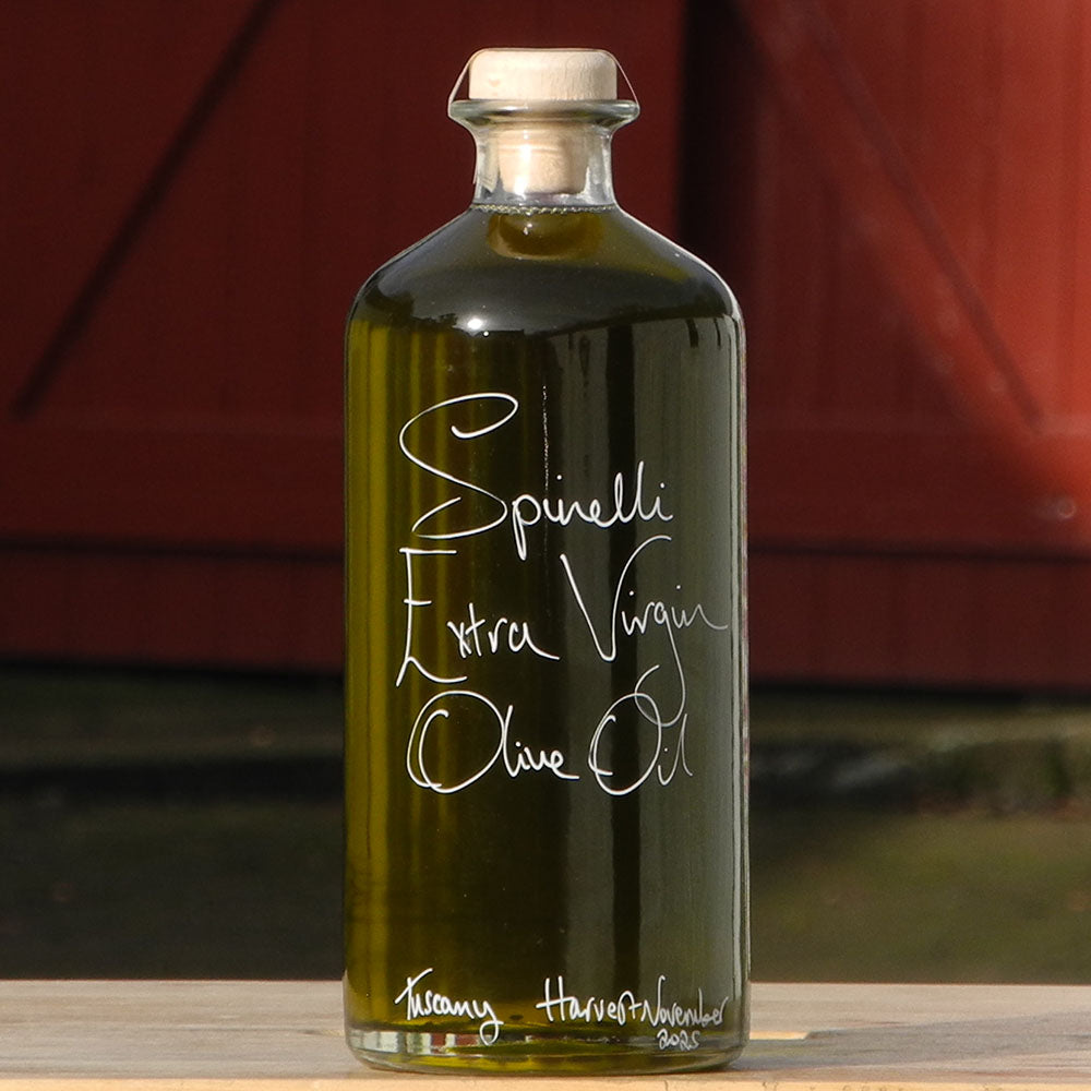 700ml bottle of Spinelli Tuscan Extra Virgin Olive Oil from Portugal with handwritten bottle message in white pen  in front of the red shutters at Glenlair Steading.