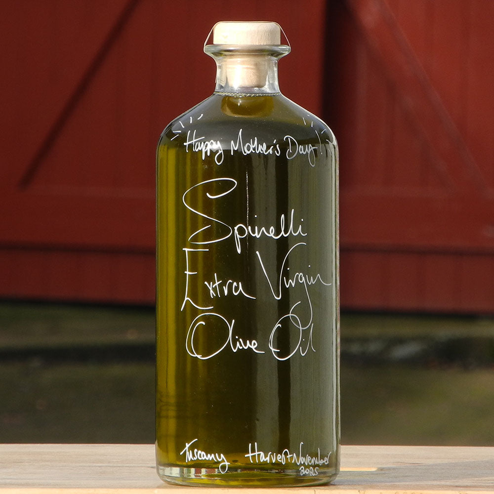 700ml bottle of Spinelli Tuscan Extra Virgin Olive Oil from Portugal with handwritten bottle message in white pen  in front of the red shutters at Glenlair Steading with personalised message that says Happy Mothers Day