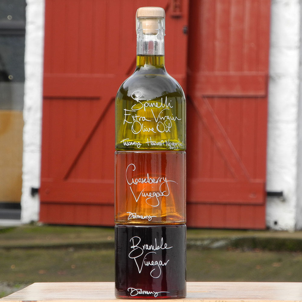 The Tuscan Oil and Vinegar Stacking Gift Set where three clever stacking Impilabile 250ml bottles have been filled with our fresh Spinelli Tuscan Extra Virgin Olive Oil, Gooseberry Vinegar and our Bramble Vinegar, both from Edinburgh. The labels are handwritten in white pen in front of the red shutters at Glenlair Steading.